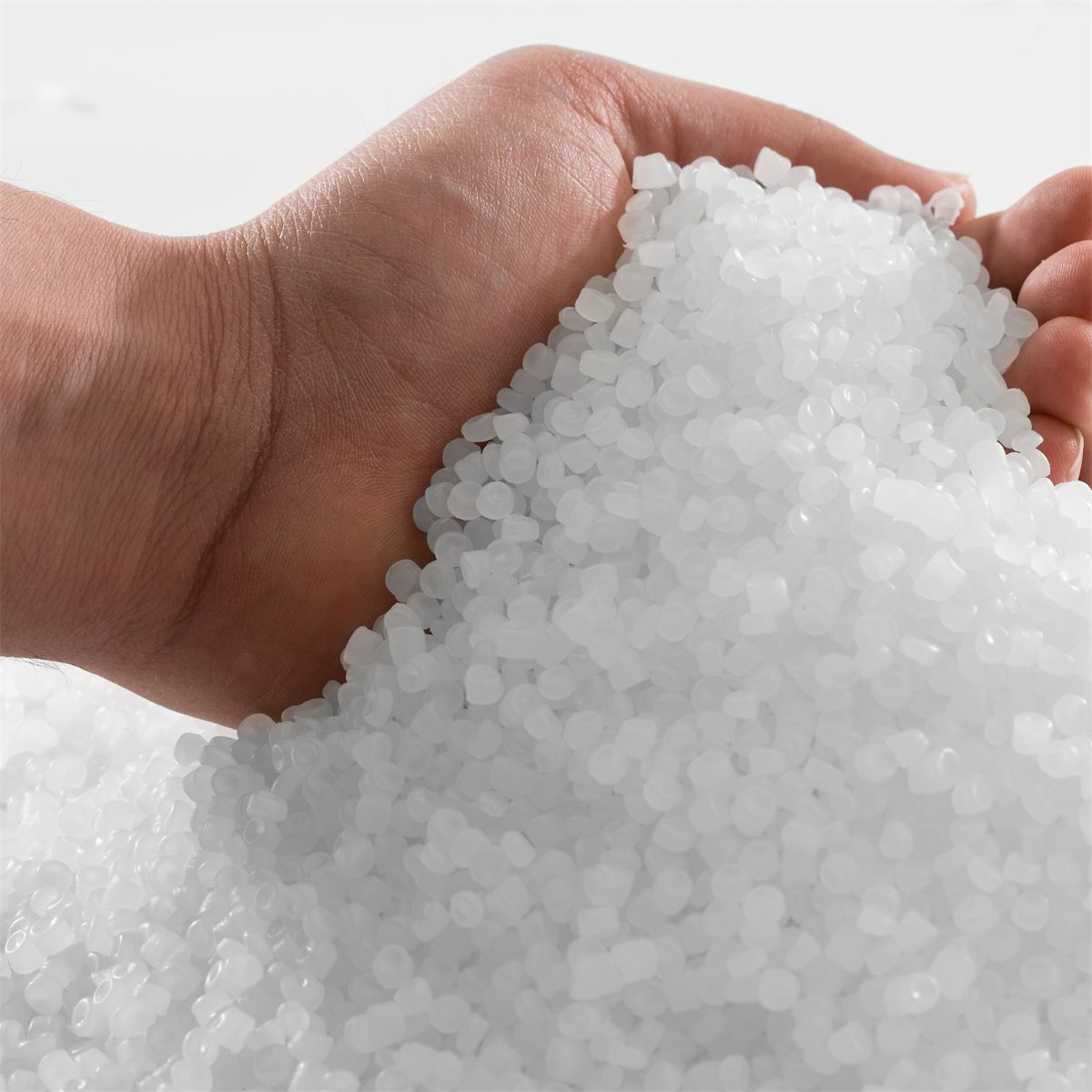 Mano sosteniendo pellets de resina plástica